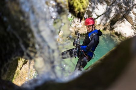 Adventurous man in wetsuit conquers a waterfall while canyoning madeira in Ribeira das Cales.
