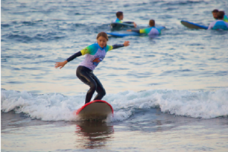 A young woman gracefully rides a surfboard in the ocean during a surf lesson, showcasing her skills and love for the sport.