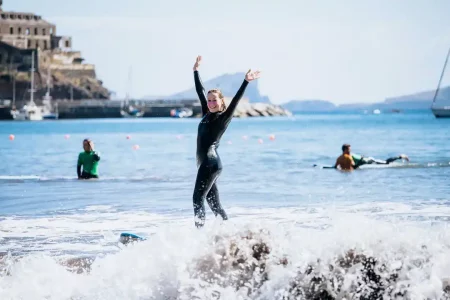 In a Surf Experience, a woman in a wetsuit gracefully balances on a surfboard, displaying her expertise in the water.